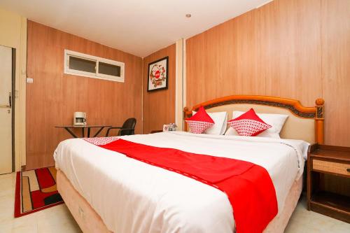 a bedroom with a large bed with red and white pillows at Super OYO Naomi Heritage in Surabaya
