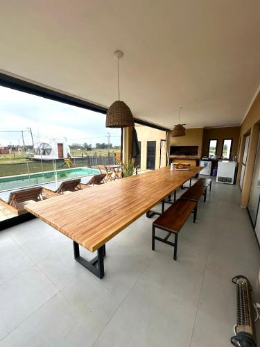 a long wooden table in a room with a pool at Glamping privado con pileta y quincho in San Vicente