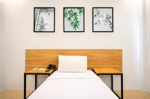 a bed in a room with three pictures on the wall at Bambu Suites in Puerto Princesa City
