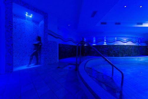 a person standing next to a swimming pool in a blue room at Hotel Parco Delle Agavi in Ischia
