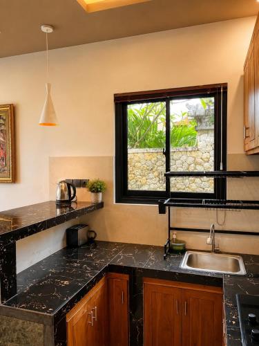a kitchen with black granite counter tops and a window at Cahya Pandawa Villa in Nusa Dua