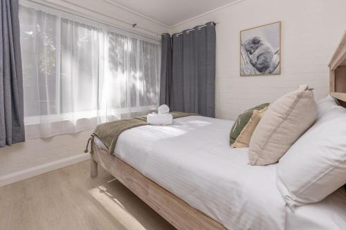 a bedroom with a large white bed with a window at Amaroo Cottage Smiths Lake in Smiths Lake