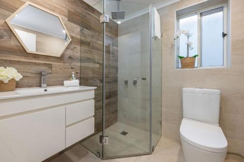 a bathroom with a toilet and a glass shower at Amaroo Cottage Smiths Lake in Smiths Lake