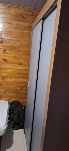 a bathroom with a toilet and a glass door at Casa de Temporada BR 470 in Cafundó