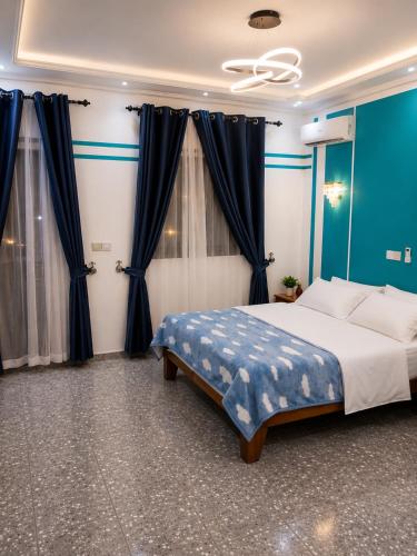 a bedroom with a large bed with blue curtains at Résidence Tango - Appartements Meublés - 4 types in Bafoussam
