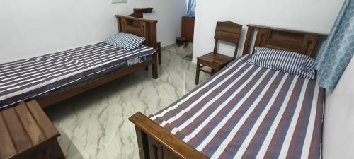 two twin beds in a room with chairs at Santha Residency in Ambātturai