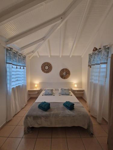 a bedroom with a bed with two green towels on it at Les Gîtes Blue Karaib in Sainte-Anne