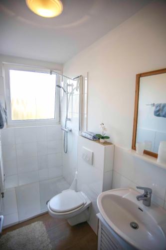 a white bathroom with a toilet and a sink at Ferienwohnung Wieben in Sankt Peter-Ording