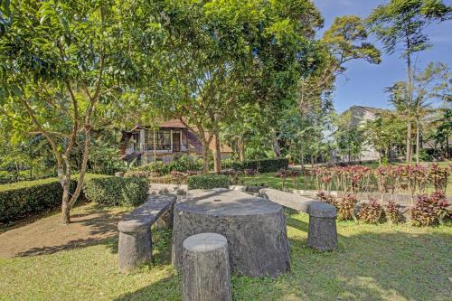 a park with stone benches and trees and a house at Hotel O Villa Inn App Trawas Bintaro Syariah in Kemloko-gede