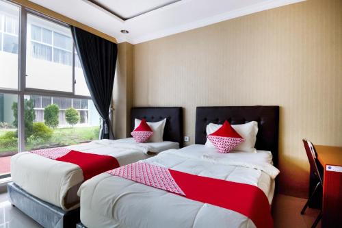 two beds in a hotel room with red and white pillows at Collection O 3431 Hotel Alpha Bandara in Palembang