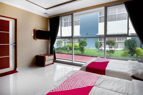 a bedroom with a bed and a large window at Collection O 3431 Hotel Alpha Bandara in Palembang
