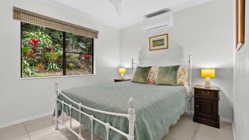 a bedroom with a bed and a window at Honeybee House Cottage in the Rainforest in Kuranda