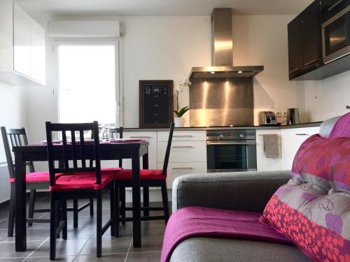eine Küche mit einem Tisch, Stühlen und einem Sofa in der Unterkunft Appartement Copenhague Disneyland in Montévrain