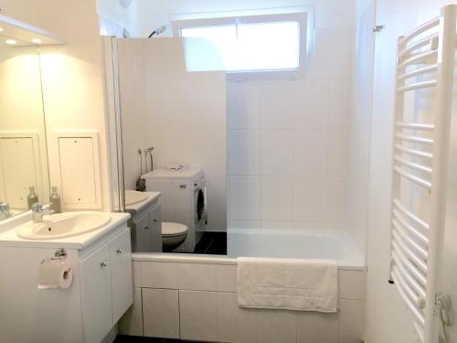 uma casa de banho branca com uma banheira e um lavatório em Appartement Copenhague Disneyland em Montévrain