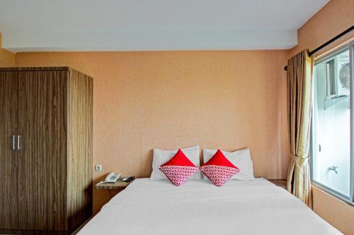 two red pillows on a white bed in a room at Hotel O Tridasa in Medan