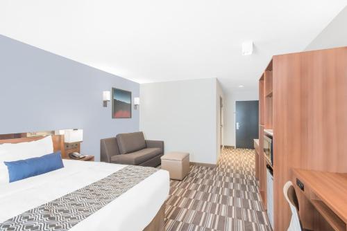 a hotel room with a bed and a chair at Microtel Inn & Suites by Wyndham Binghamton in Binghamton
