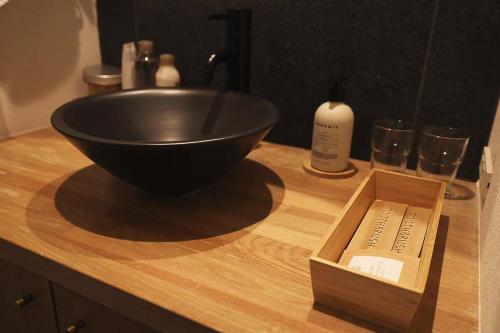 a black bowl on a counter with a bottle and glasses at The Cabin by Deep Gorge in Kita-karuizawa
