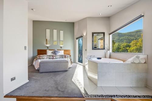 a bedroom with a tub and a bed and a window at Bushland in Halls Gap