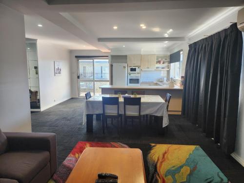a living room with a table and a kitchen at Crest Motor Inn in Queanbeyan