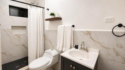 a white bathroom with a sink and a toilet at Lumina loft express minutes to consulate in Hermosillo