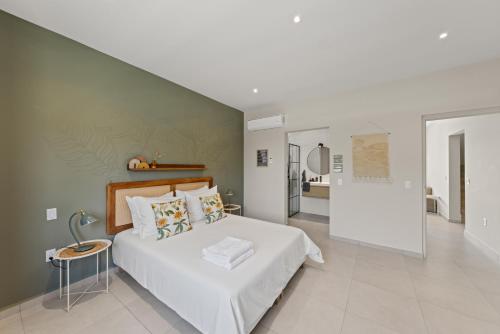 a bedroom with a white bed and a green wall at Villa Anosia Laman i Tera in Westpunt