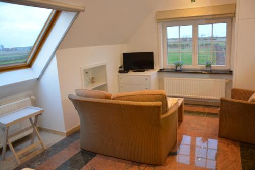 a living room with a couch and a tv at PS Orion in Wenduine