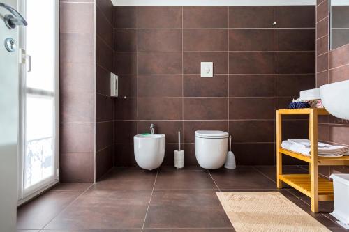 a bathroom with two toilets and a tiled wall at Affittacamere Polvara Trentuno in Lecco