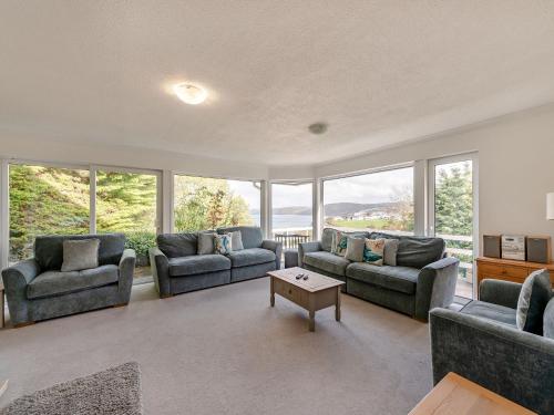 a living room with couches and chairs and windows at Five Bays View in Aberporth