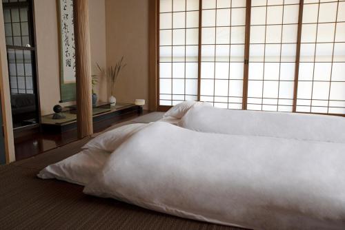 a bed with white sheets and pillows in a room at goemon-inn in Akita