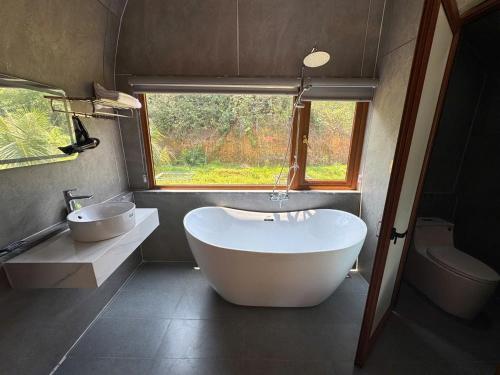 a bathroom with a large tub and a sink at Green Valley Retreat in Phong Nha