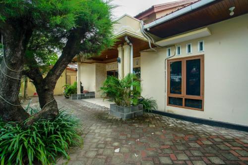 a house with a tree and a brick walkway at Capital O 90643 Suri Guest House Syariah in Padang