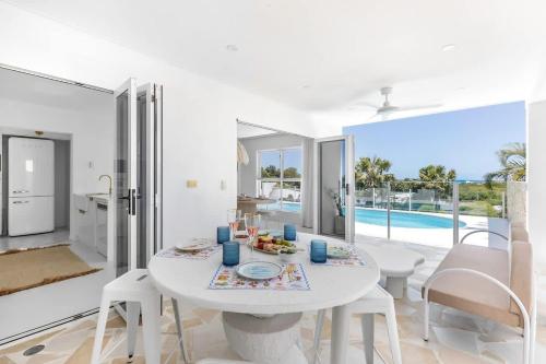 a white dining room with a white table and chairs at WhitsunStays - The Cyclades in Eimeo