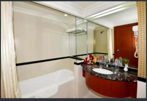a bathroom with a sink and a bath tub at Abadi Suite Hotel & Tower in Jambi