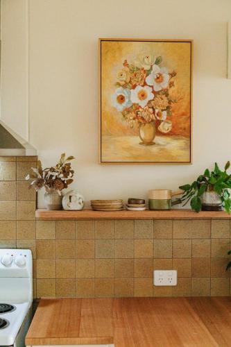 a kitchen with a painting of a vase of flowers at Georgie Bay St Helens in St Helens