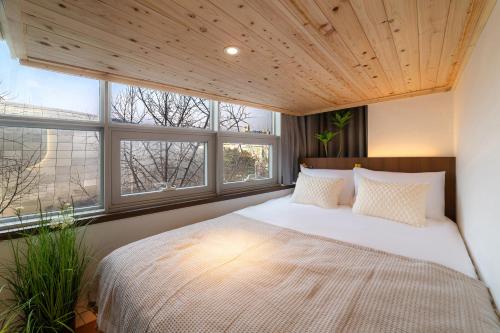 a bedroom with a large white bed with windows at LAHA Boutique DDP Dongdaemun in Seoul