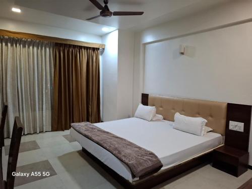 a bedroom with a large white bed with a window at Hotel Pride Executive in Satara