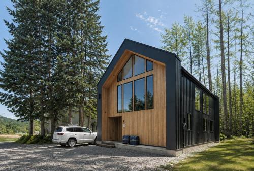 a black and wooden house with a white car parked in a parking lot at Hakuba Bubu Chalet by Jade Villa in Hakuba