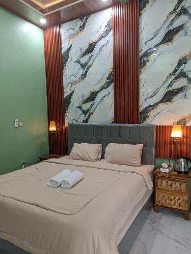 a bedroom with a large bed with a painting on the wall at Nanda Harum Villa in Sangyang