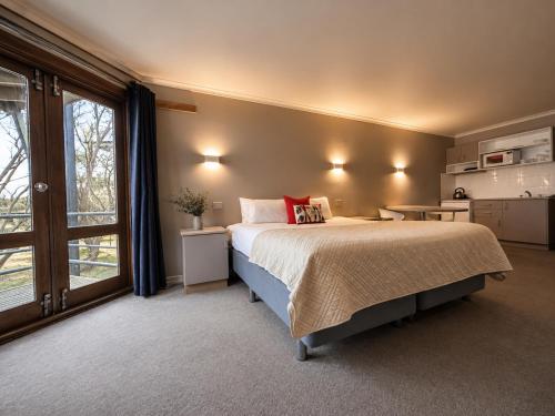 a bedroom with a bed and a large window at High Plains Lodge Rooms in Dinner Plain