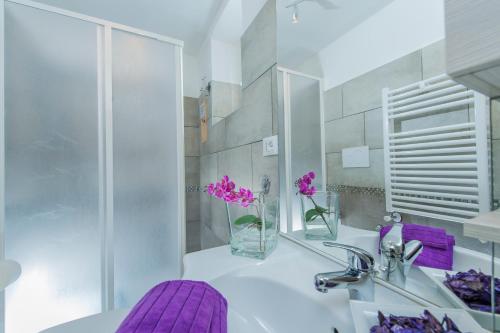 a bathroom with a sink and a vase of purple flowers at FL Apartments Charming Flat in the heart of Trastevere in Rome