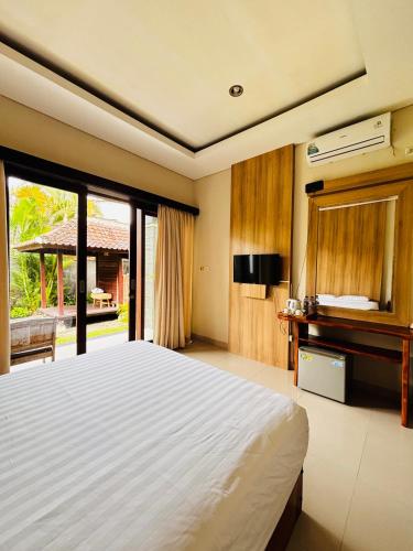 a bedroom with a bed and a desk and a window at Guest House Reisya in Nusa Dua