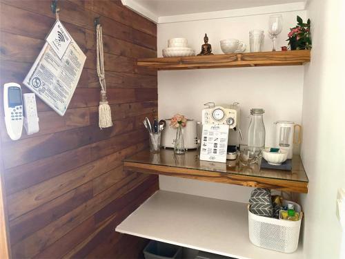 a kitchen with wooden walls and a shelf with a coffee maker at Nibbana Bungalows in Hinkong