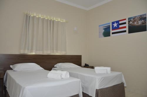 - 2 lits dans une chambre avec des draps blancs dans l'établissement Hotel Brasil, à Guanhães