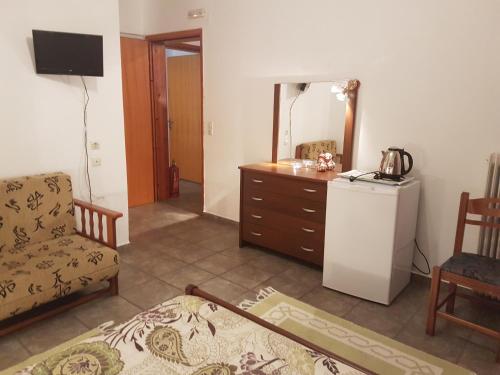 sala de estar con silla, cómoda y nevera en Sofia Rooms, en Kalambaka