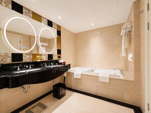 a bathroom with a tub and a large mirror at Trans Hotel Jakarta in Cibubur