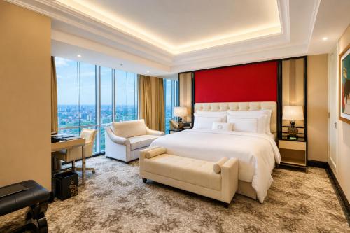 a bedroom with a large white bed and a red wall at Trans Hotel Jakarta in Cibubur
