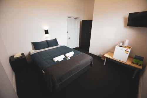 a bedroom with a bed with two towels on it at Queenscliffe Hotel in Kingscote
