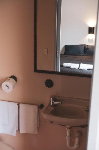 a bathroom with a sink and a mirror and a bed at Queenscliffe Hotel in Kingscote