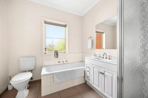 a white bathroom with a toilet and a sink at Modern home in Highton in Highton