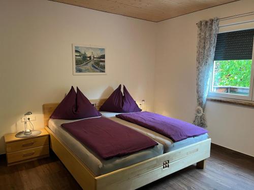 a bedroom with a bed with purple pillows and a window at Appartements Dürnle in Mühldorf
